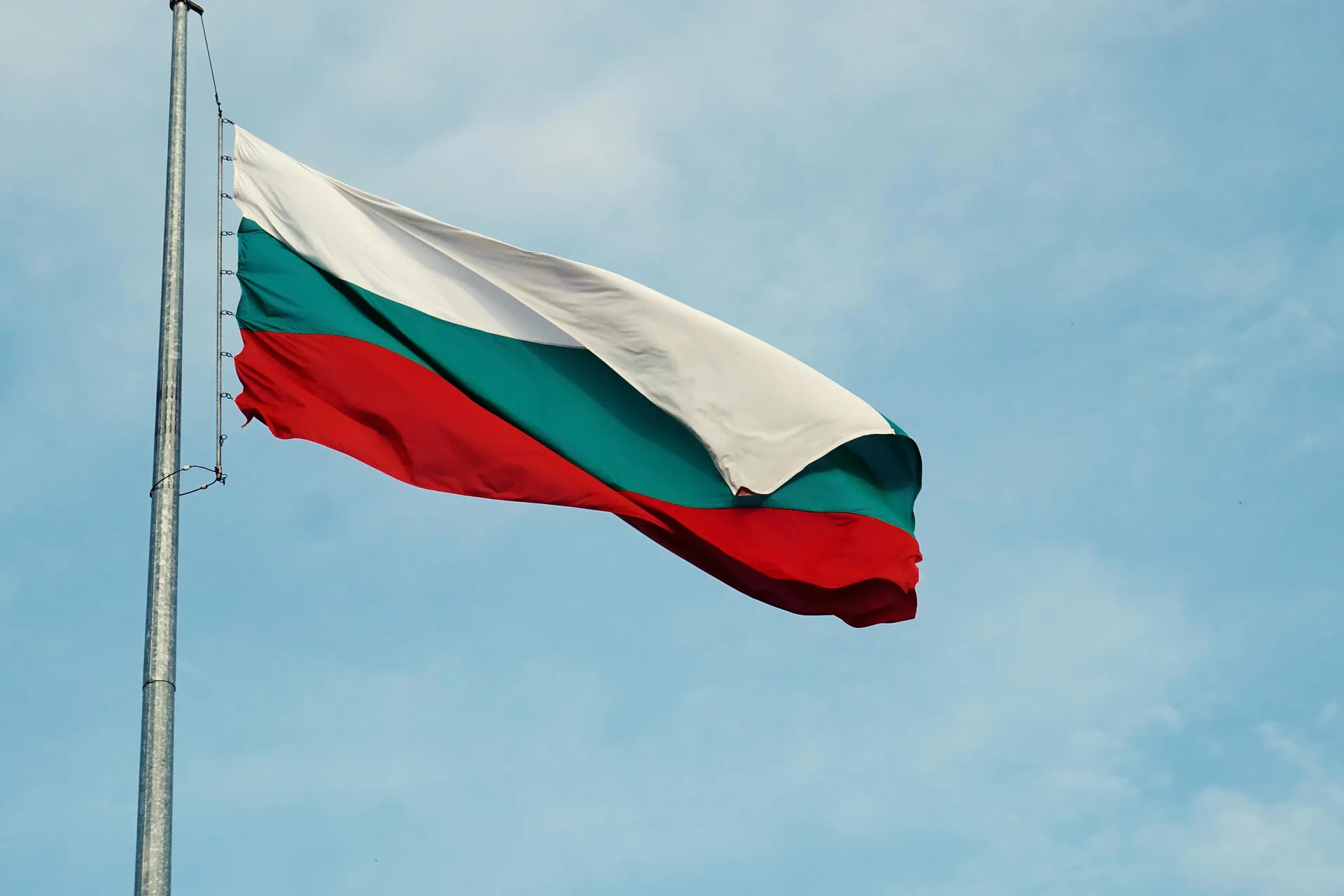 Drapelul național al Bulgariei fluturând pe un catarg pe fundalul unui cer senin în Varna.